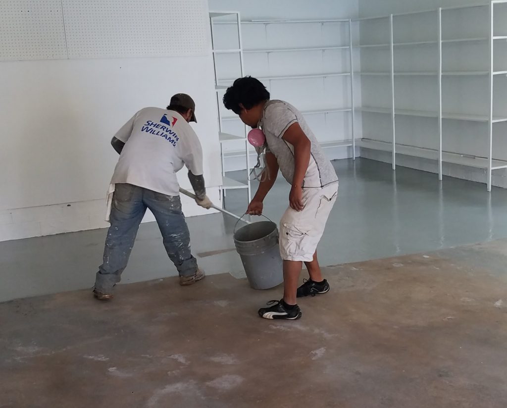 Garage floor epoxy contractor Klappenberger & Son applying the first of two coats of epoxy paint for garage